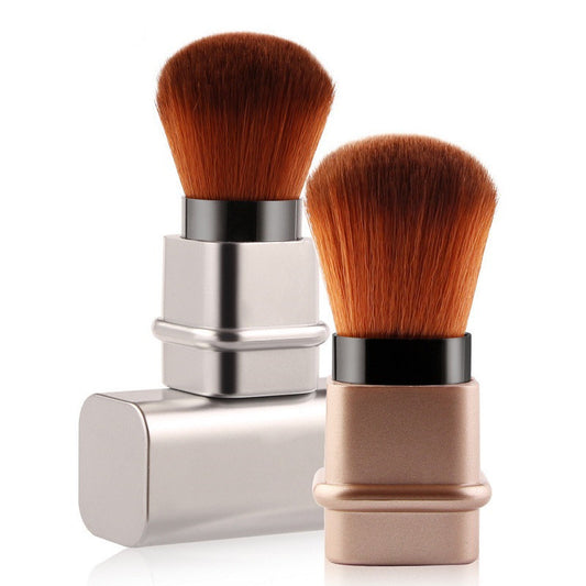 Portable makeup brush with soft man-made fiber bristles and lightweight plastic handle. Available in square gold and silver. Compact, travel-friendly, and gentle on all skin types.