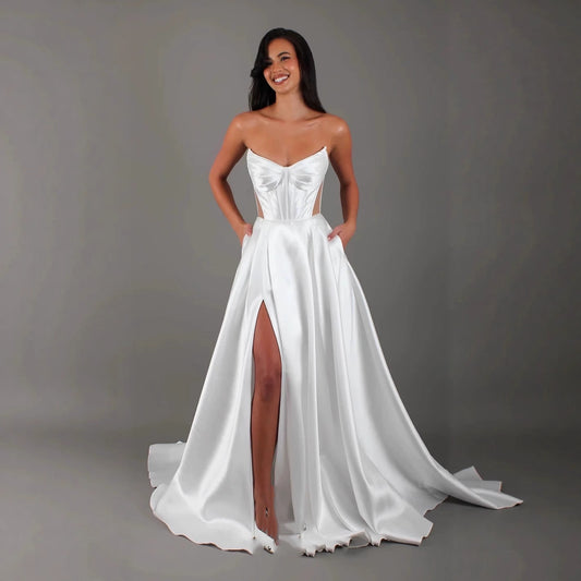 Elegant sleeveless mid-waist long dress with folding details. Available in white and ivory, sizes 2 to 26W. Perfect for formal occasions.